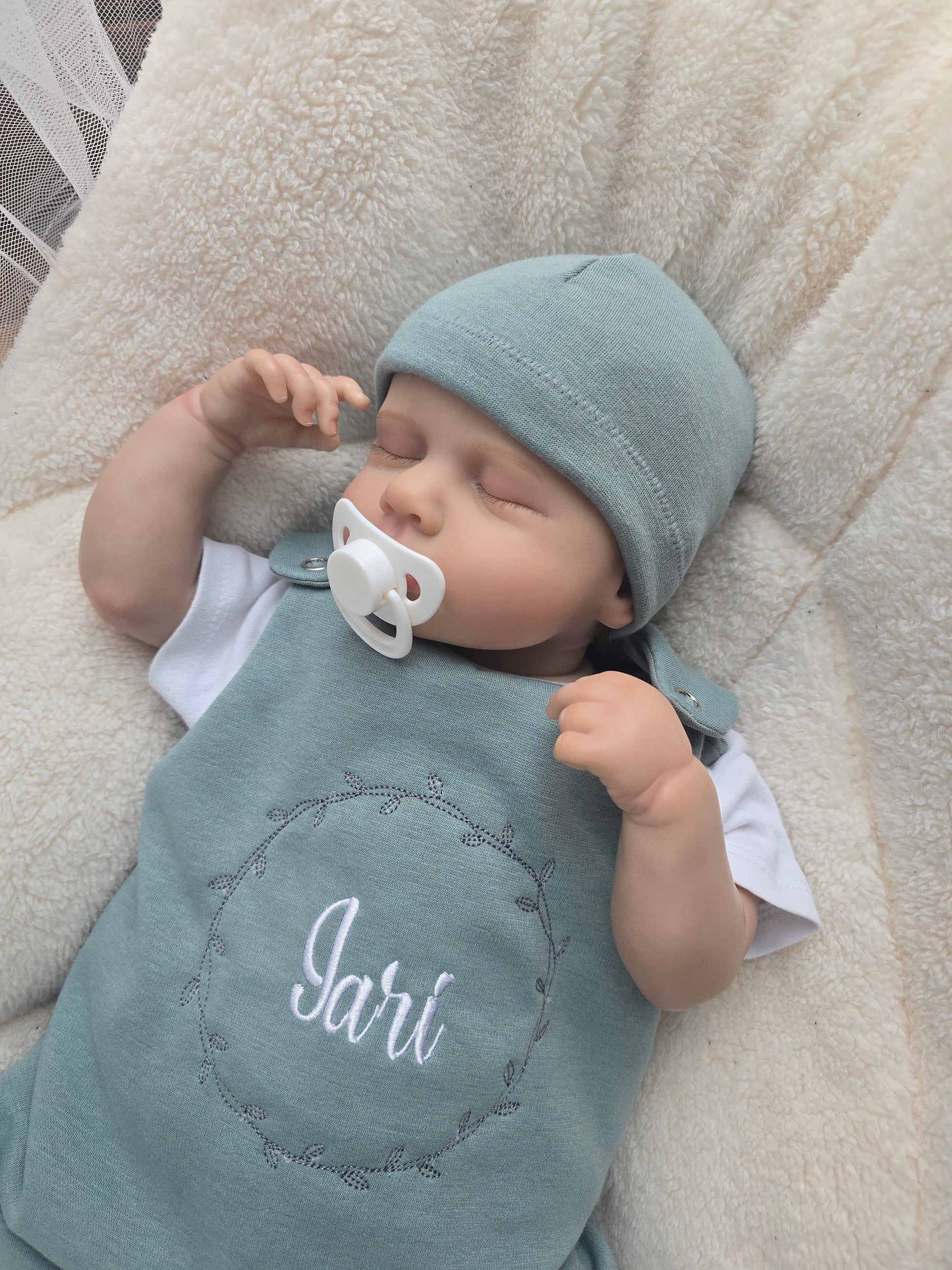 Baby Strampler gefüttert aus Sweat mit individueller Stickerei auf dem Vorderteil. Inklusive dazu passender Mütze aus Sweat.