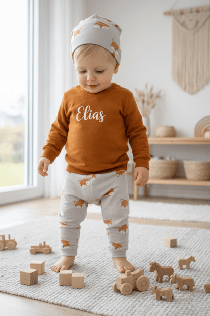 In Deutschland, handgemachtes Baby und Kinderset, bestehend aus einem Pullover mit Namen, einer dazu passenden Hose und Mütze.