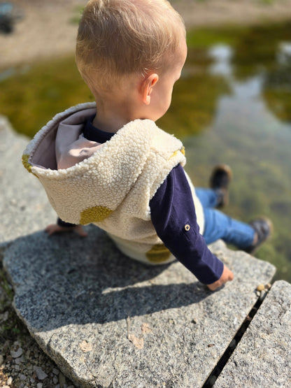Weste aus einem flauschigem Teddystoff nach Wahl mit Kapuze und Reißverschluss. Gefüttert mit einem beigen Innenfutter.